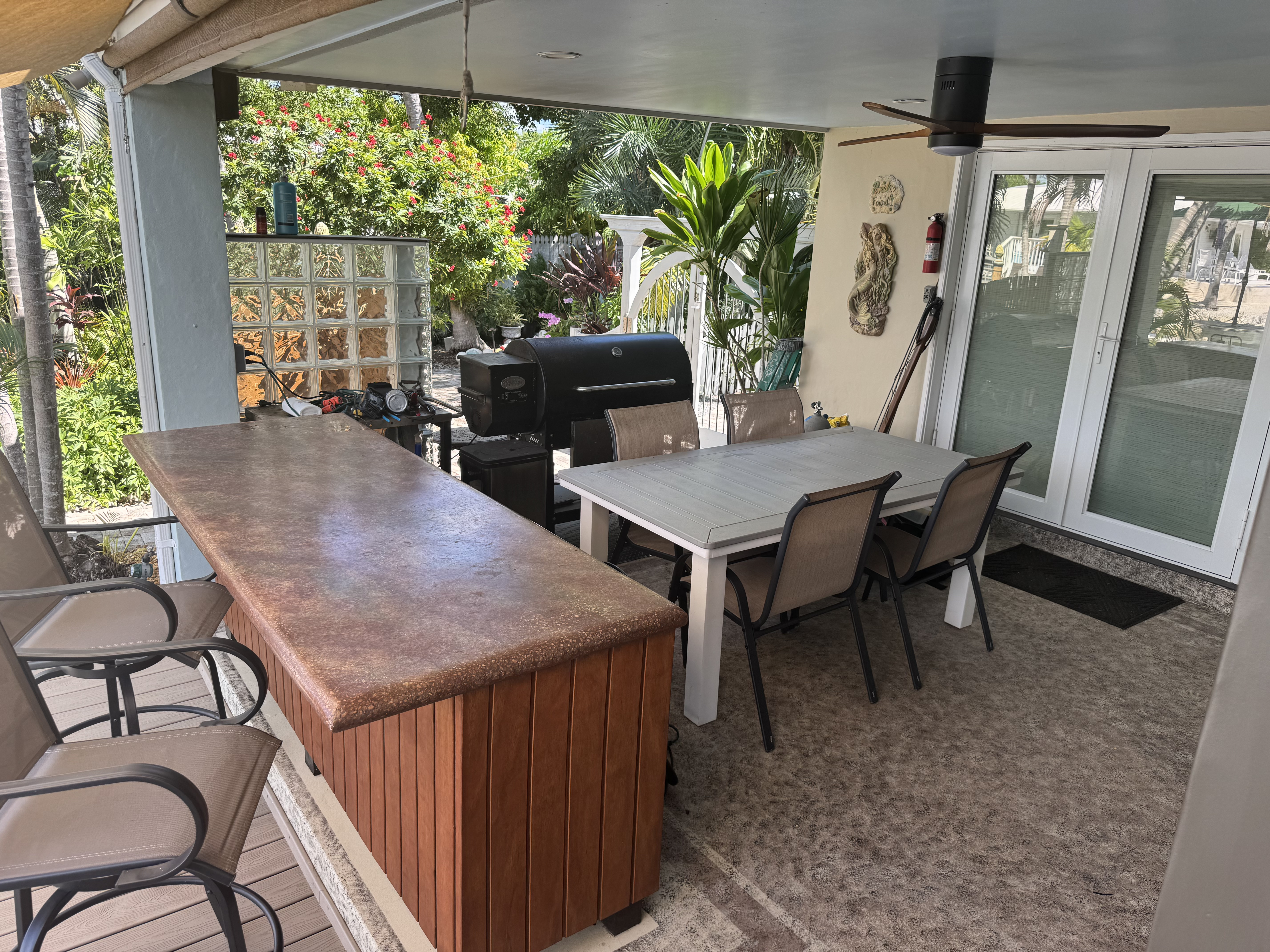 Second back porch features a new party bar with barstools, overlooking both the water and the palm garden. There is a Louisiana pellet grill here as well as fans, table & chairs, and outdoor freezer.